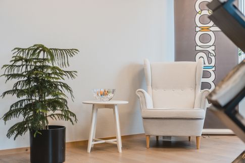 Vit fåtölj med litet vitt bord grön växt 